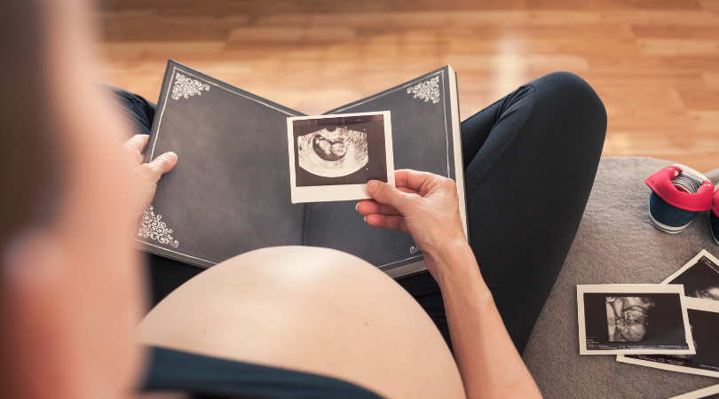 pregnant woman looking at ultrasound photos