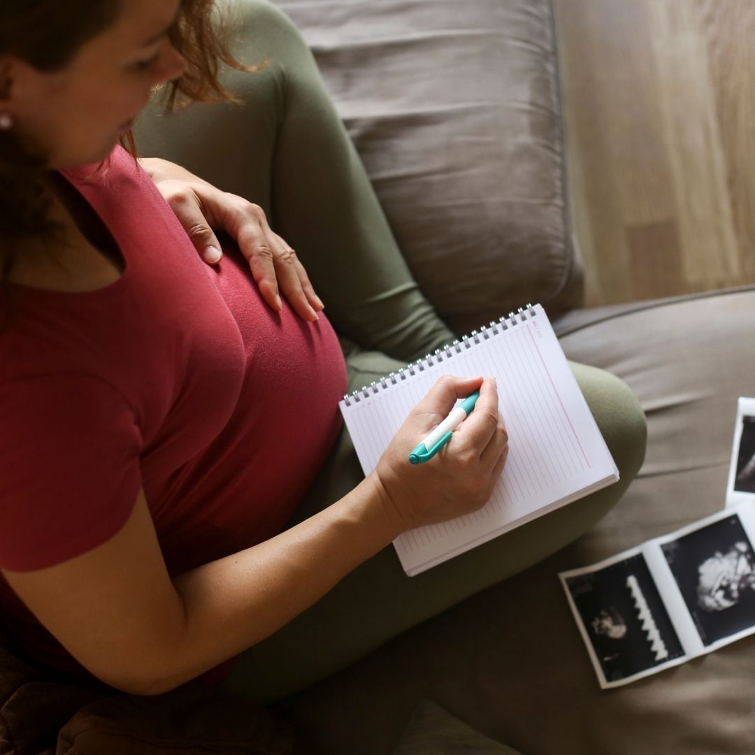 Pregnant woman writing Popular Baby Names 