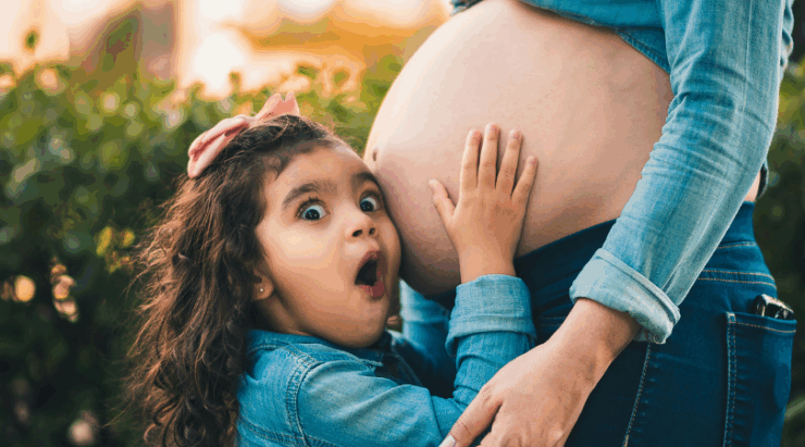 Sibling listening to mommy belly